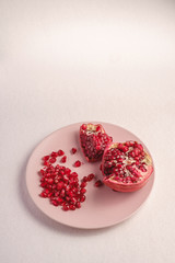Fresh tasty sweet peeled pomegranate with red seeds in pink plate on white background, angle view, healthy food fruits