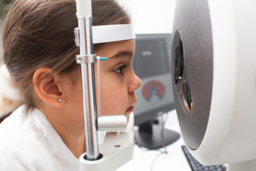 Tomography of eyes of a little girl patient. Advanced eye test equipment. Girl's face close up. Vision correction