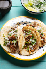 Mexican slow cooked lamb tacos also called barbacoa on turquoise background