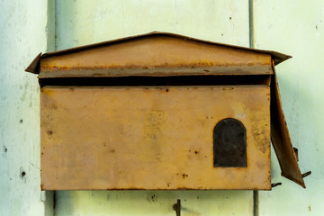 The old red mailbox made of metal attached to the front of the house