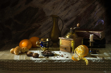 Still life with oranges and coffee, vintage manual coffee grinder, bronze vase, candlestick.