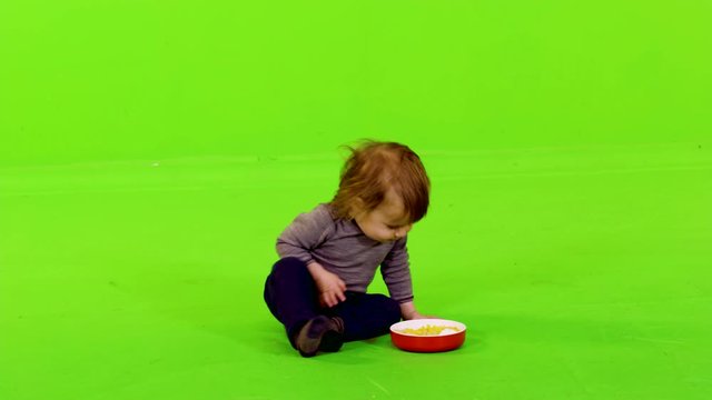 Cute little toddler eating with her hands, full shot over green screen.