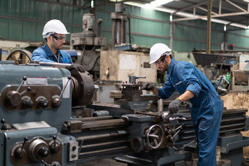 Industrial engineers in safety uniforms wearing white safety helmets are inspecting work by tools.  and on the job training he works in industrial machinery.