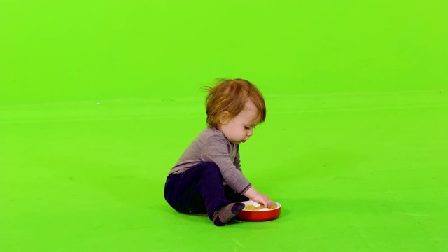 Cute little toddler nodding and eating with her hands, full shot over green screen.