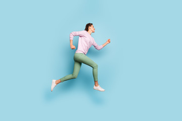 Fototapeta na wymiar Full length photo of beautiful lady jumping high up rushing finish line running marathon champion competitive soul wear casual pink sweater green pants isolated blue color background