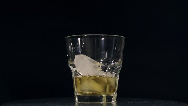 Whiskey in a glass goblet with ice on a black background