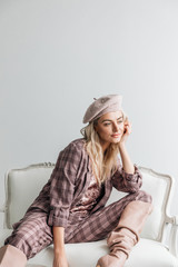 Beautiful blonde fashion woman in brow checked dress. Trendy young woman in shabby chic white interior.