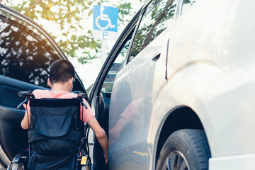 Lifestyle of Asian special child on wheelchair going up on a car parked in a disabled parking...