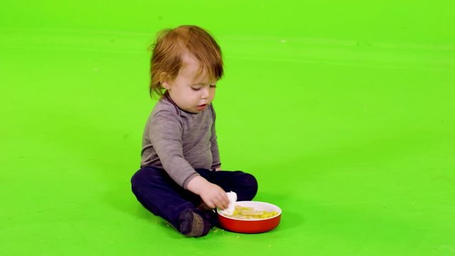 Cute little toddler playing and eating with her hands, full shot over green screen.
