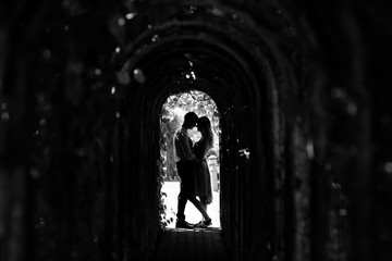 Full length silhouette of man and woman hug in the arches with plants in sunny day. Love story. Poland, Warsaw. Black and white photo