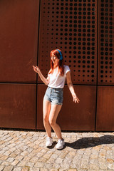 Young woman moves in dance on sunny street alone