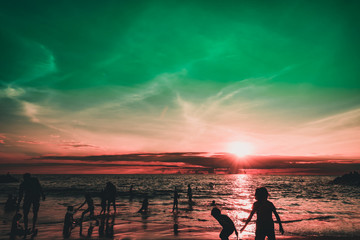Fototapeta premium Dramatic sky and clouds on the beach at sunset. Silhouettes of people on the beach at sunset. City residents are enjoying a weekend by the sea. 