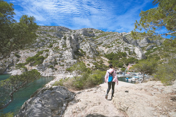 A female hiker is walking on the pathway to the national park of the calanques of Marseille, Provence region. There are very beautiful and stunning views.