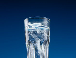 Glass with cold water and ice on a blue background