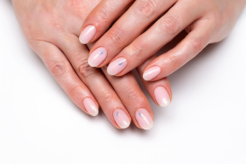 pink nude manicure with crystals and white sparkles on short oval nails on a white background close-up