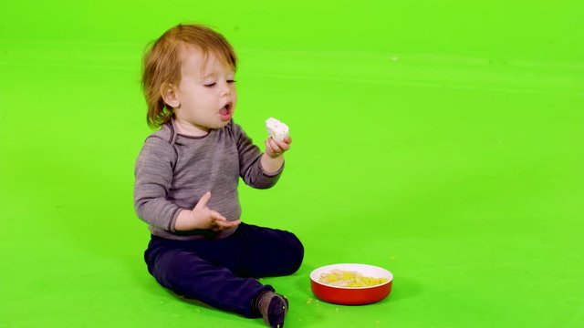 Happy little toddler playing and eating with her hands, full shot over green screen.