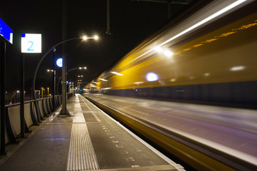 Blurred train by motion at night at station Arnhem south, Netherlands