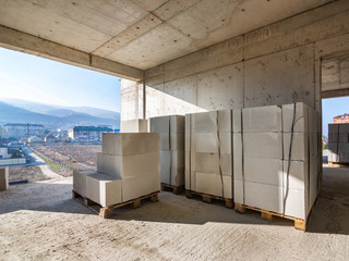 Several whole packages of aerated concrete blocks on pallets in a building under construction,...