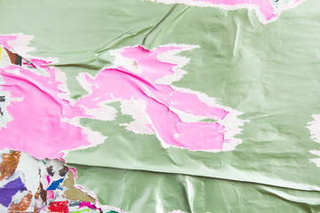 Old pink and grey torn and peeling paper posters and placards layers on dirty billboard with rough...