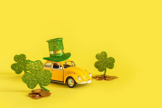 Minsk, Belarus - February 2020: holiday of St. Patrick's Day .. A yellow toy car is carrying a hat and clover holiday symbol on a yellow background. Holiday Irish Patrick's Day postcard with retro car
