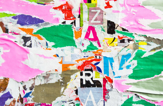 Old torn shabby and peeling paper posters and placards layers on dirty billboard with rough surface texture background.