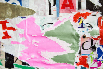 Torn and ripped urban paper posters on billboard with old dirty peeling placards layers texture...