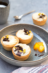 homemade shortbread tartlets or cupcakes with delicate cream and orange jam, decorated with chocolate chips. natural sweets concept. cozy tea party