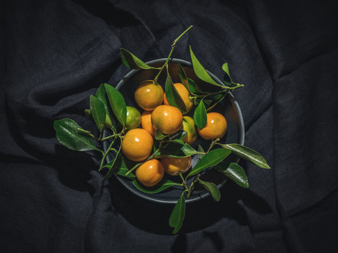 Tangerines With Green Leaves In Blue Bowl On Dark Background. Overhead Shot.