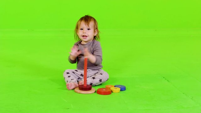 Cute toddler playing with Stacking Rings, clapping her hands after succeeding, over green screen.