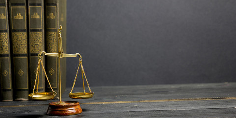 Law concept - Open law book with a wooden judges gavel on table in a courtroom or law enforcement...