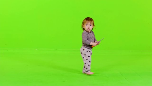 Cute little toddler running  from side to side, holds a toy, happy, full shot over green screen. 