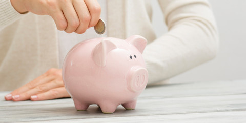 woman hand putting money coin into piggy for saving money wealth and financial concept.