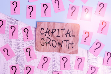 Word writing text Capital Growth. Business photo showcasing increase in the value of an asset or investment over time Scribbled and crumbling papers with thick cardboard above wooden table