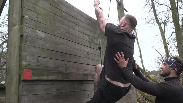 Men climbing up wall with rope during Tough Mudder obstacle course / assault course - Slow motion - Stock Video Clip Footage