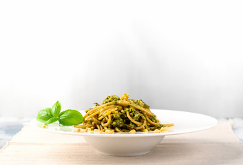 Plate of pasta with pesto sauce on light background