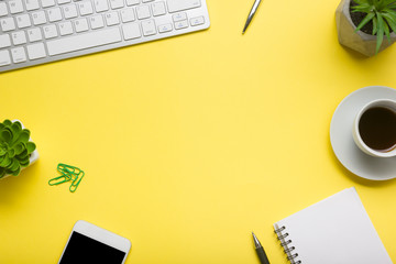 Yellow desk office with laptop, smartphone and other work supplies with cup of coffee. Top view...