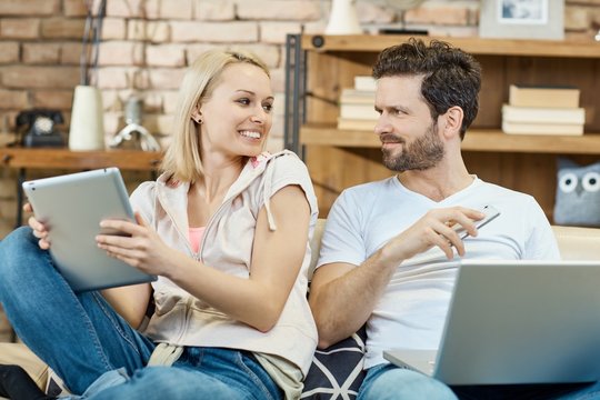 Young couple with laptop mobile and tablet