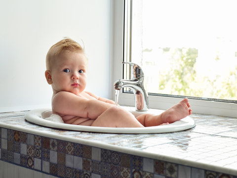 cute adorable  baby having bath in washing sink