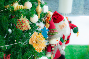 Golden flower and box toy mobile hanging on the Christmas tree And the festival celebrating the New Year and background Santa Claus doll