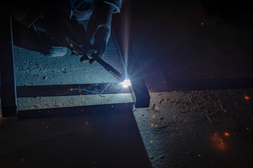 Welding a metal frame in workshop with argon welding