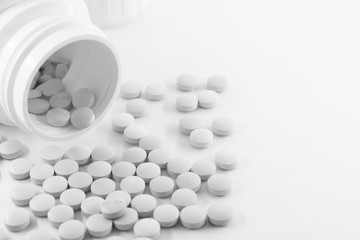 Pill bottles on table, white medical pills spilling out of a drug bottle