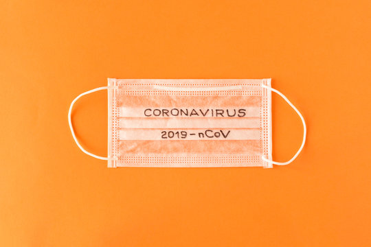 CORONAVIRUS. 2019-nCoV.  The inscription CORONAVIRUS 2019-nCoV on a protective medical mask on an orange background. The concept of virus protection.