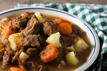 Irish beef stew with carrots and potatoes on wooden table. Close up