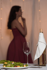 selective focus of elegant, thoughtful girl standing near served table in restaurant