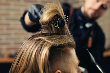 Barber drying male hair in hairdressing salon