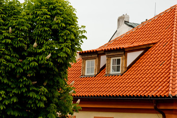 Prague. 05.10.2019: Low light detail of patina red roof top. Prague Lesser Town typical roofing material. Old roofing of clay tiles. Various orange shades and stains.