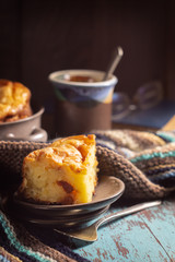 Cottage cheese casserole, cup of tea and a woolen scarf on a wooden table