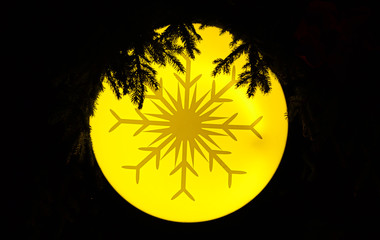 A snow flake design on an yellow christmas tree ornament