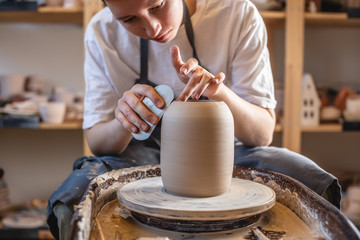 Potter working on a Potter's wheel making a vase. Master processing the formed jug giving it the correct shape