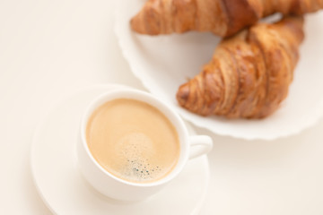 Croissants on a white plate and a cup of coffee. Breakfast is delicious and healthy.